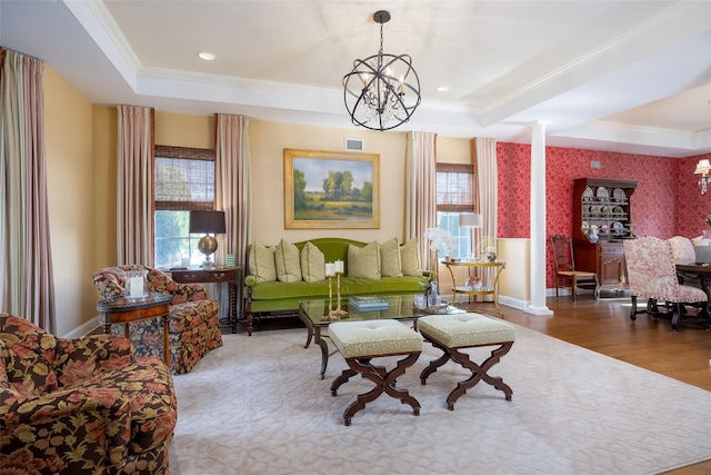 living area featuring an inviting chandelier, ornamental molding, a tray ceiling, and wood finished floors