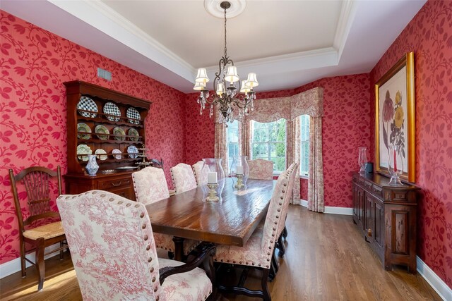 dining room featuring an inviting chandelier, baseboards, wallpapered walls, wood finished floors, and ornamental molding