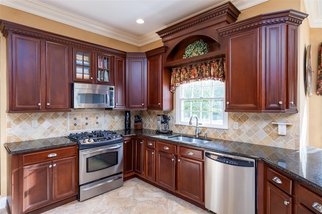 kitchen with a sink, dark stone counters, stainless steel appliances, reddish brown cabinets, and ornamental molding