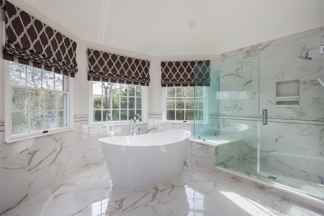 full bath featuring a freestanding bath, wainscoting, a marble finish shower, marble finish floor, and tile walls