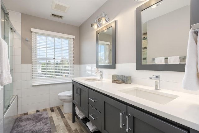 bathroom with visible vents, a sink, toilet, and tile walls