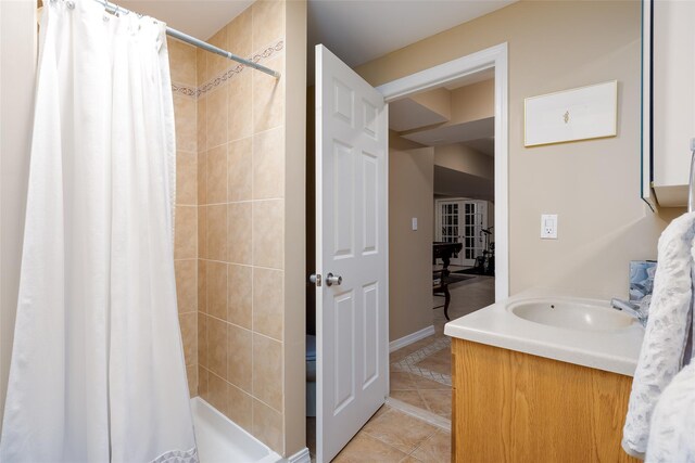 bathroom with a sink, baseboards, tile patterned flooring, and a shower stall