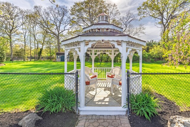exterior space with fence, a gazebo, a wooden deck, a shed, and an outbuilding