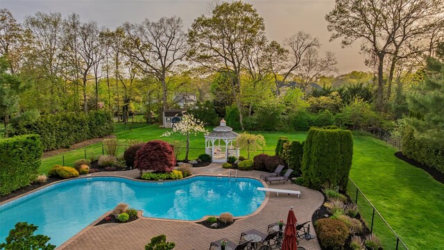 pool with a lawn, a diving board, a gazebo, and fence private yard