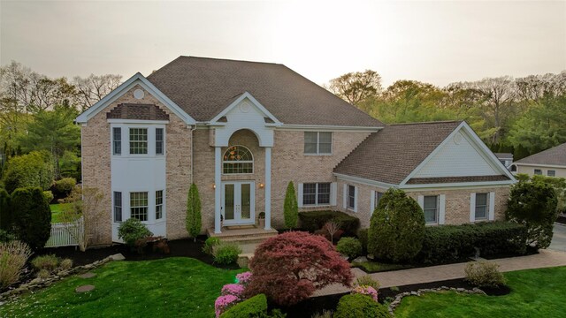 view of front of property featuring french doors, a front yard, and brick siding