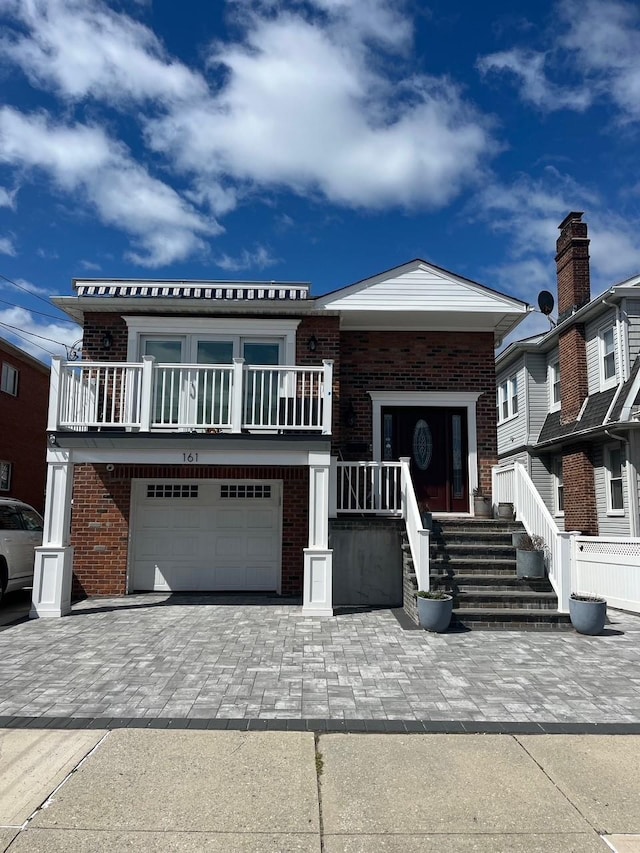 view of front of property with brick siding, a garage, a balcony, and decorative driveway