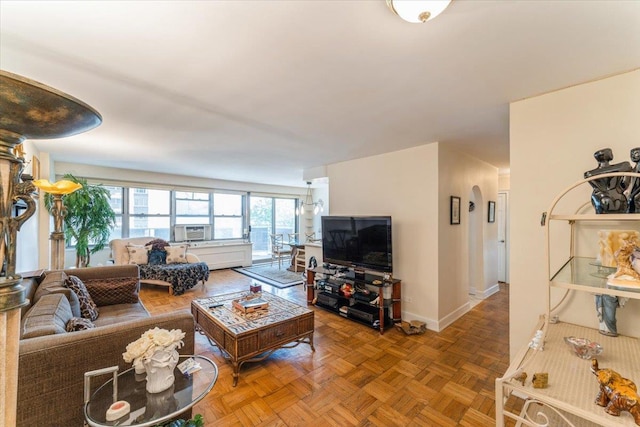 living area with arched walkways, baseboards, and cooling unit