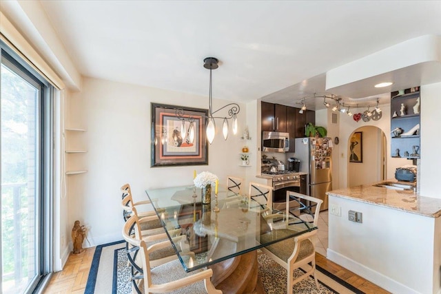 dining space featuring arched walkways and baseboards