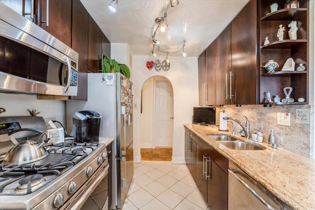 kitchen featuring open shelves, a sink, arched walkways, stainless steel appliances, and tasteful backsplash