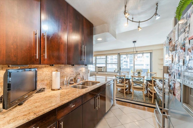 kitchen with light tile patterned flooring, light stone countertops, tasteful backsplash, a sink, and appliances with stainless steel finishes
