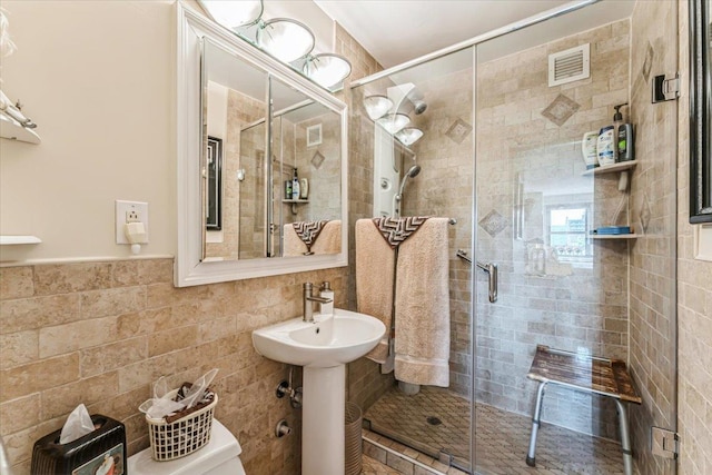 full bath with visible vents, a stall shower, and tile walls