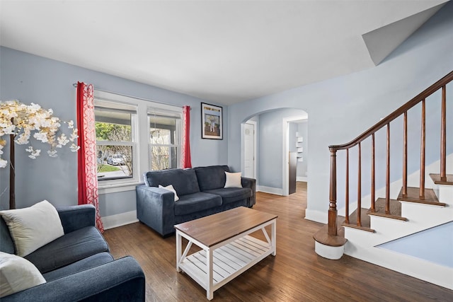 living area featuring stairway, arched walkways, baseboards, and wood finished floors
