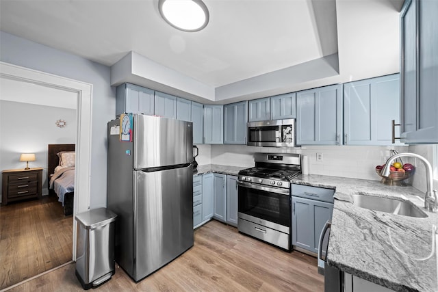 kitchen featuring a sink, appliances with stainless steel finishes, light stone counters, and tasteful backsplash