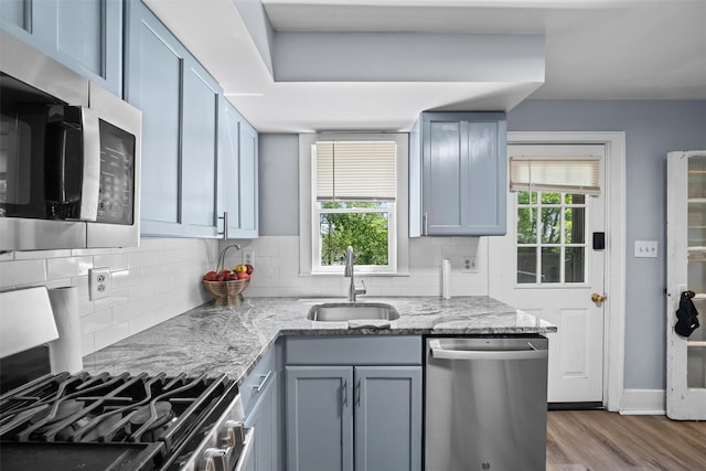 kitchen featuring stainless steel appliances, a wealth of natural light, a sink, and tasteful backsplash