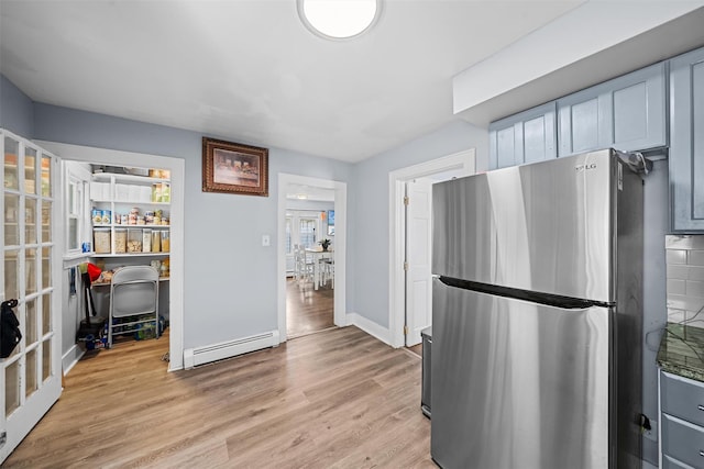 kitchen with french doors, baseboards, freestanding refrigerator, a baseboard heating unit, and light wood finished floors