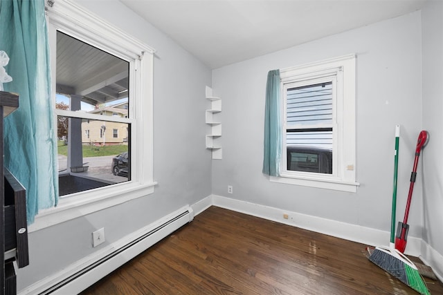spare room with baseboards, a baseboard heating unit, and dark wood-type flooring