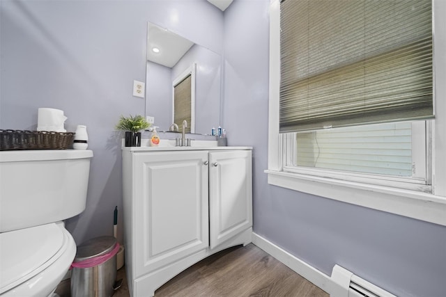 bathroom featuring baseboard heating, wood finished floors, vanity, baseboards, and toilet