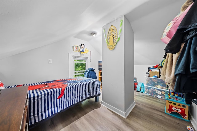 bedroom featuring baseboards, vaulted ceiling, and wood finished floors
