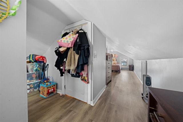 corridor with wood finished floors, baseboards, and lofted ceiling