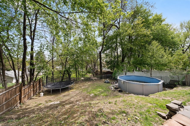 view of yard featuring a fenced in pool, a fenced backyard, and a trampoline