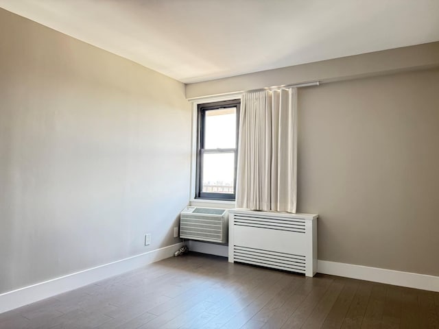 unfurnished room with radiator heating unit, baseboards, and dark wood finished floors