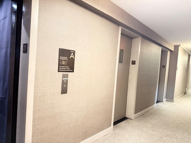 hall with baseboards, carpet flooring, and elevator