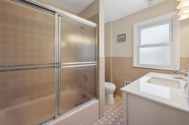 219 Third Ave, Pelham, NY 10803 - full bathroom featuring toilet, vanity, tile walls, shower / bath combination with glass door, and a wainscoted wall