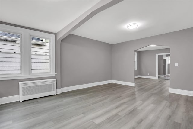 62-22 80th Rd, Glendale, NY 11385 - bonus room featuring radiator heating unit, arched walkways, baseboards, and wood finished floors