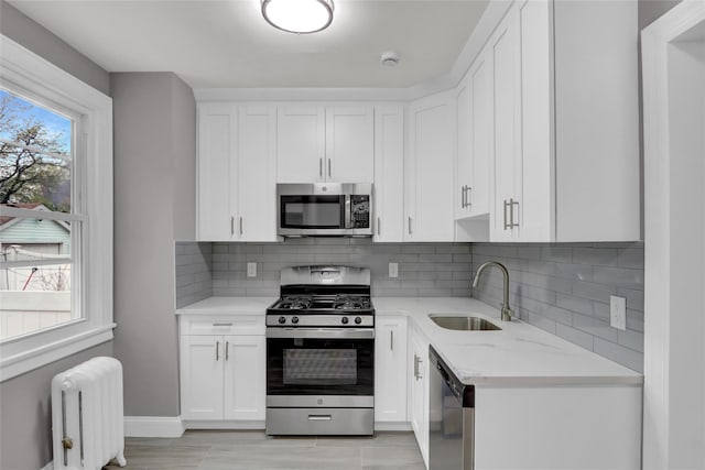 62-22 80th Rd, Glendale, NY 11385 - kitchen featuring appliances with stainless steel finishes, radiator, a sink, and white cabinetry