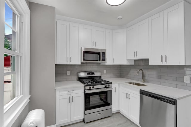 62-22 80th Rd, Glendale, NY 11385 - kitchen with appliances with stainless steel finishes, a sink, white cabinets, decorative backsplash, and light stone counters