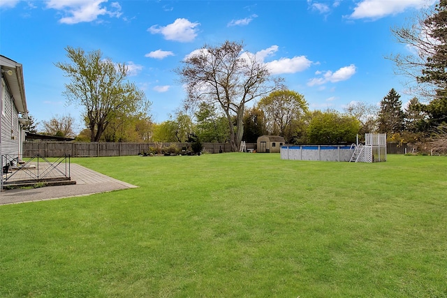 view of yard featuring a fenced backyard, a storage unit, a fenced in pool, and an outdoor structure