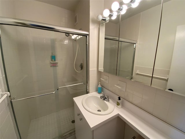 bathroom featuring vanity, tasteful backsplash, a shower stall, and visible vents