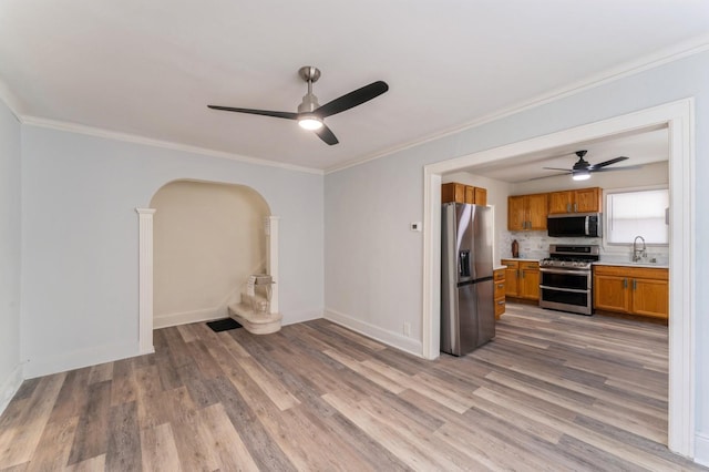 interior space with ceiling fan, a sink, ornamental molding, and light wood-style flooring