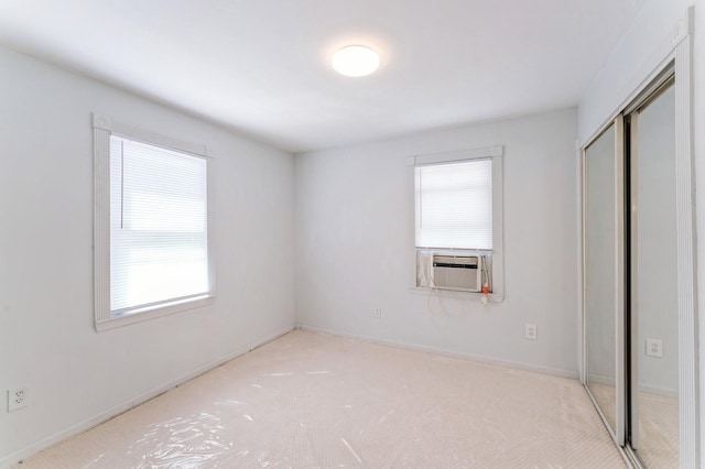 unfurnished bedroom with carpet floors, a closet, cooling unit, and multiple windows