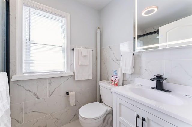 bathroom with tile walls, vanity, and toilet