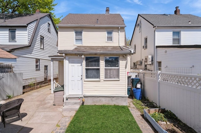 rear view of property featuring a patio, a fenced backyard, a garden, and a chimney
