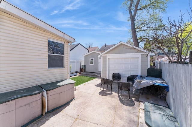 view of patio / terrace with fence, an outbuilding, and driveway