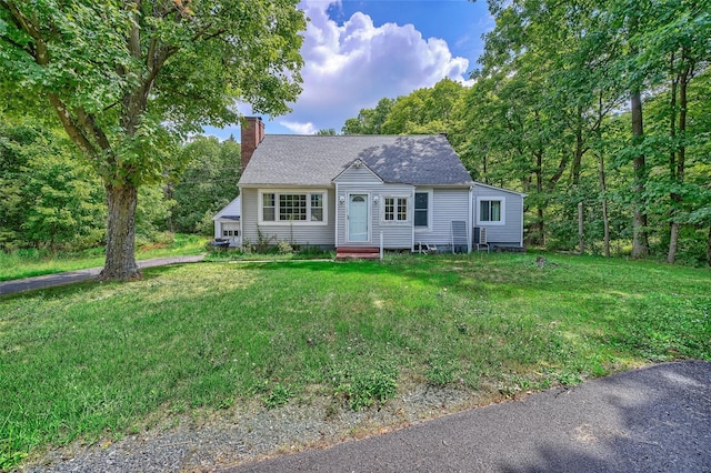 view of front of property with a shingled roof, a chimney, and a front yard