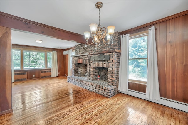 unfurnished living room featuring wood-type flooring, wooden walls, radiator heating unit, and a notable chandelier