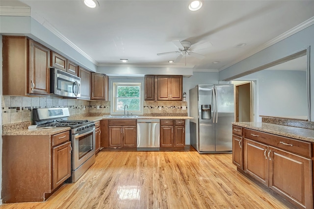 kitchen featuring brown cabinets, ceiling fan, appliances with stainless steel finishes, and light wood-style floors