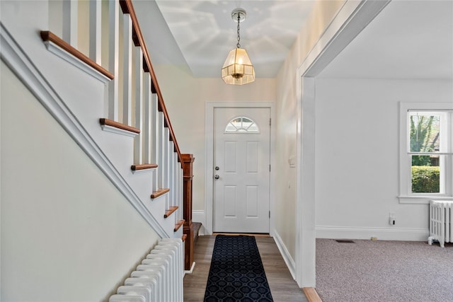 entrance foyer with baseboards, stairs, and radiator heating unit
