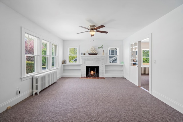 unfurnished living room with radiator heating unit, ceiling fan, carpet, and a fireplace