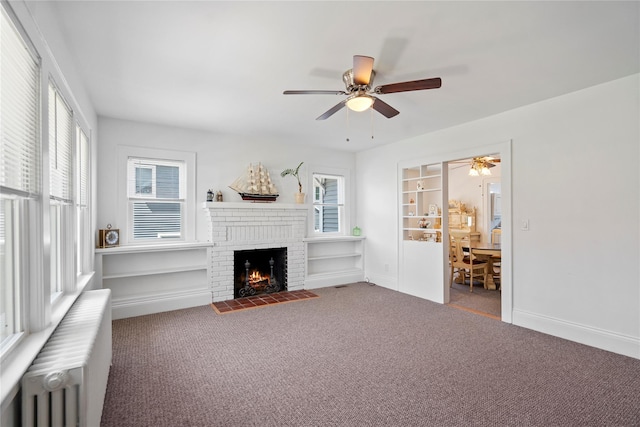 living area with radiator heating unit, carpet, a ceiling fan, and a brick fireplace