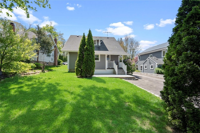 rear view of house featuring a porch and a yard