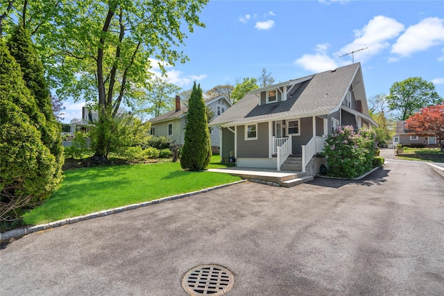 view of front of house featuring a shingled roof and a front yard
