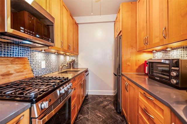 kitchen with appliances with stainless steel finishes, a sink, baseboards, backsplash, and brown cabinetry