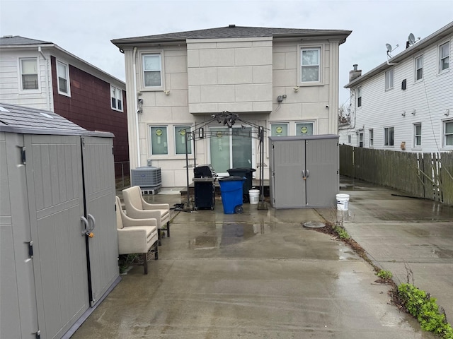 back of property with an outdoor structure, a fenced backyard, a patio area, and a storage unit