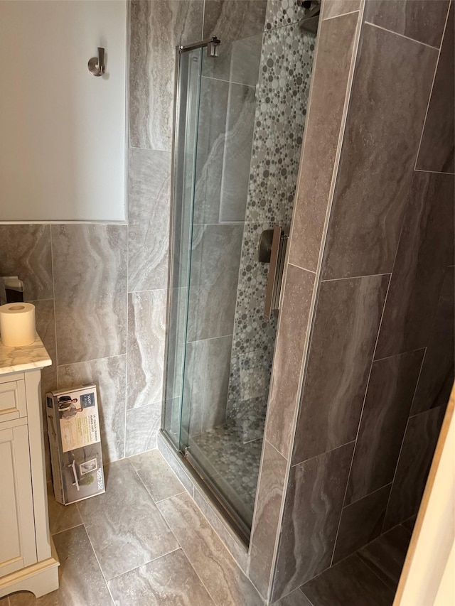 bathroom with vanity, tile walls, and a shower stall