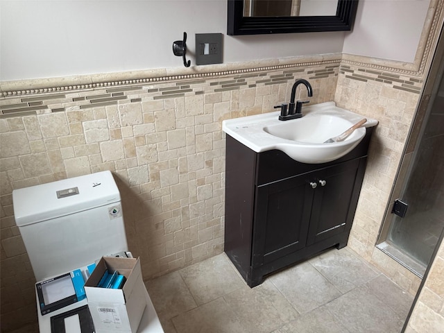 bathroom featuring tile walls, a wainscoted wall, vanity, and toilet