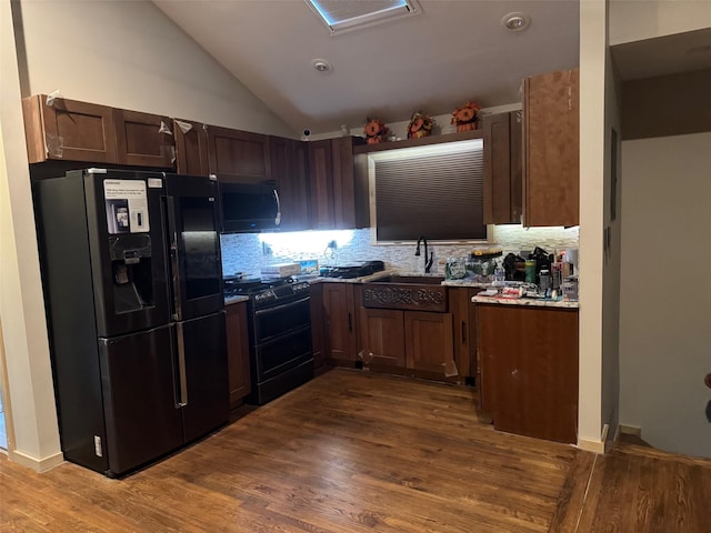 kitchen with black fridge, a sink, range with two ovens, dark wood-type flooring, and backsplash